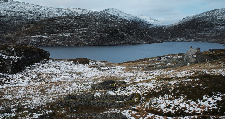 Wintery scene of a hilltop lake and isolated stone cottage