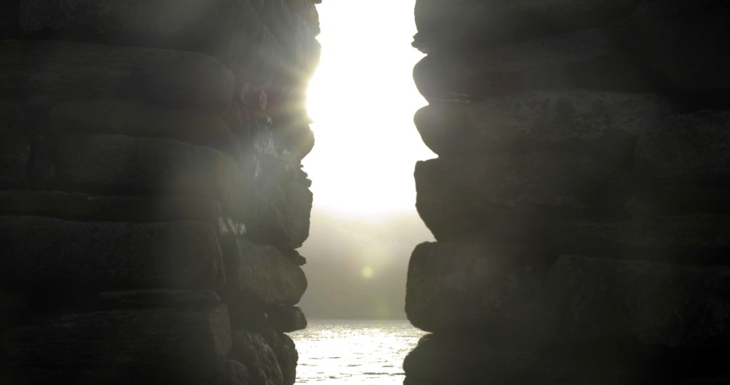 Light passes through a gap between two stone walls