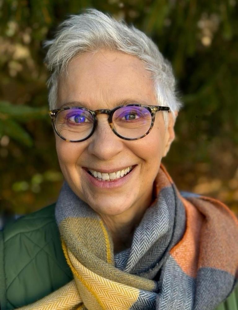 Portrait of Celia Landman with a friendly smile and wearing a cosy scarf
