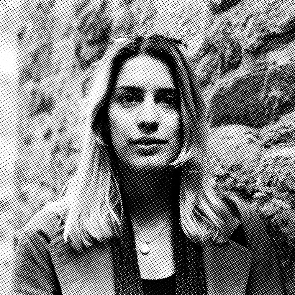 Portrait of Nadja standing in front of a stone wall